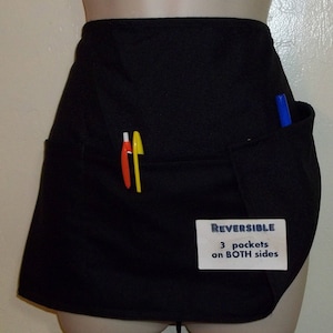 May include: Black reversible apron with three pockets on both sides. The apron has a label that says "REVERSIBLE 3 pockets on BOTH sides".