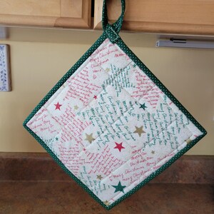 May include: A quilted Christmas pot holder with a green polka dot border and hanging loop. The white fabric features red and gold stars and the words "Merry Christmas".