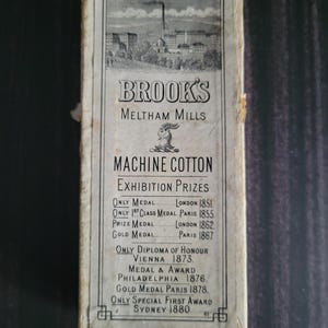 May include: Vintage Brooks Meltham Mills Machine Cotton box. The box features an illustration of a factory and text detailing exhibition prizes from 1851 to 1880. The box is rectangular and has a faded, aged appearance.
