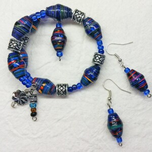 May include: A blue and multi-coloured paper bead bracelet with silver accents and a charm. Matching earrings with blue and multi-coloured paper beads.
