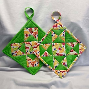 May include: Two green quilted pot holders with a fruit print. The pot holders have a loop handle.