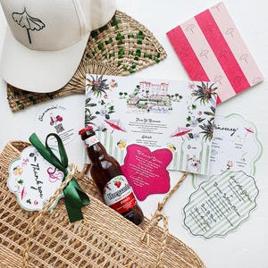 May include: A cream baseball cap with a black umbrella icon, a woven straw tote bag with a dark green ribbon, a bottle of Hoegaarden Rosée beer, and various printed wedding stationery items featuring pink stripes, floral illustrations, and text.