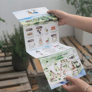 May include: A brochure for Camp Ranita, featuring a watercolor illustration of a lake and camp activities. The brochure unfolds to reveal a camp itinerary and a map of the lake lawn. The text includes "Camp Ranita" and "Lake Lawn Map."