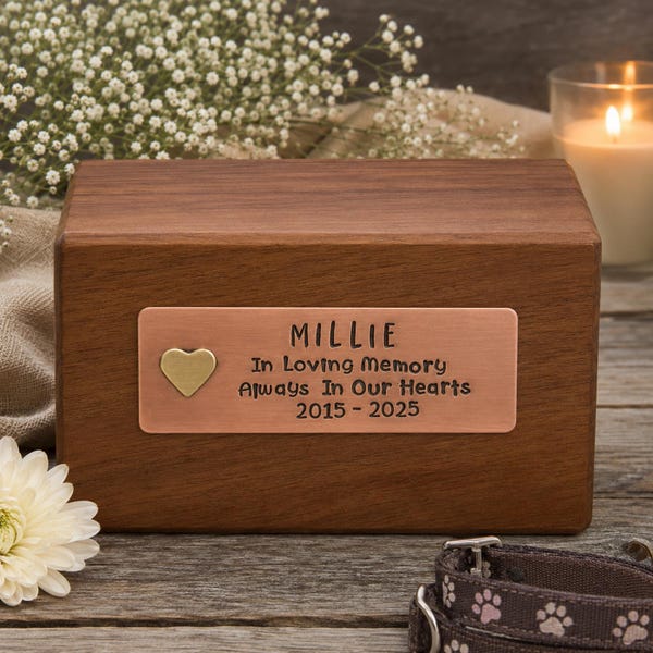 May include: A rectangular dark brown wooden cremation urn featuring a horizontal copper-colored metal plaque. The plaque is engraved with the text MILLIE, In Loving Memory, Always In Our Hearts, and 2015-2025, with a small gold heart icon.