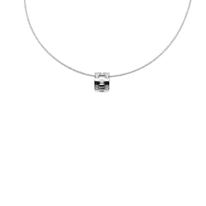 May include: A silver necklace with a square pendant set with small, clear gemstones. The pendant is suspended from a fine, wire-like chain. The design is minimalist and elegant, suitable for everyday wear or special occasions.