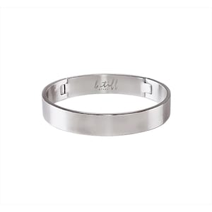 Może przedstawiać: Srebrna bransoletka typu bangle z zapięciem na zawias. Bransoletka jest grawerowana słowami "b.till steel".