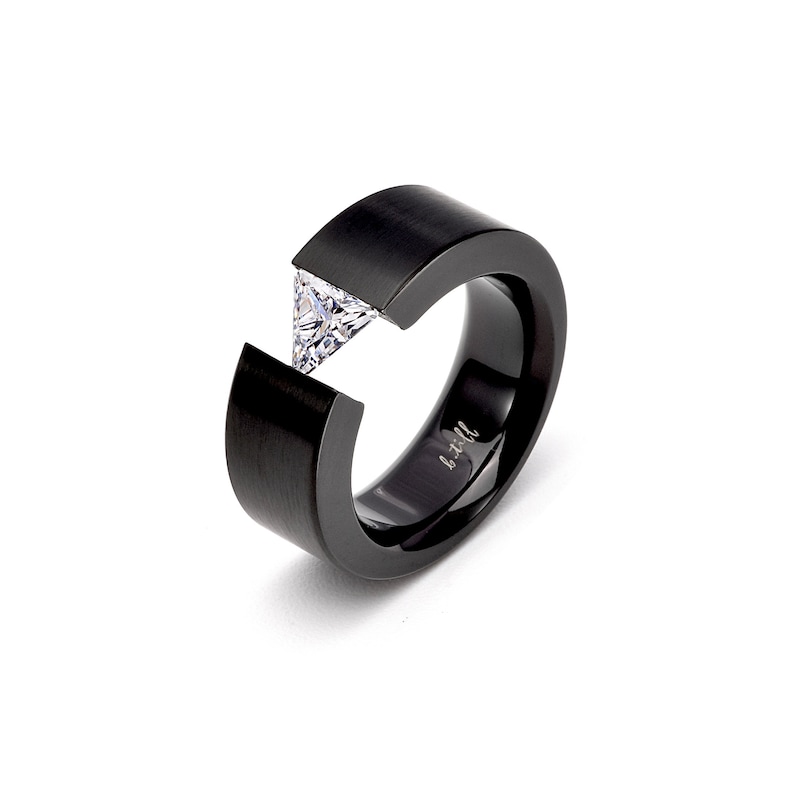Pode incluir: Um anel preto fosco com um design de banda larga e aberta. Uma &uacute;nica pedra preciosa transparente, com lapida&ccedil;&atilde;o triangular, est&aacute; cravada entre as duas extremidades da banda. O interior do anel apresenta o texto gravado b.till em cursivo.