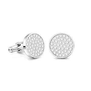 May include: A pair of silver cufflinks with a round face covered in small, sparkling white stones. The cufflinks have a classic design with a post and toggle closure, perfect for formal wear or adding a touch of elegance to any outfit.
