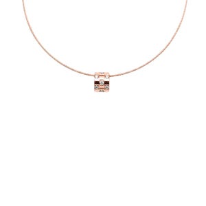 May include: A rose gold necklace with a small, square pendant. The pendant is decorated with clear, sparkling stones and a checkered design. The necklace has a fine chain, and the pendant is the central feature of the piece.