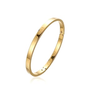 May include: A polished gold-tone bangle bracelet with a smooth, rounded surface and a hinged clasp mechanism. The bracelet features a simple, continuous circular design with a reflective metallic finish that catches the light along its curved edge.