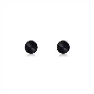 May include: A pair of circular stud earrings featuring a matte black finish with a subtle brushed metal texture. The earrings are round in shape and have a flat, disc-like profile, presenting a clean and simple design for ear ornamentation.