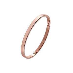 May include: Rose gold bangle bracelet. The bracelet has a simple, elegant design with a smooth, polished finish. The clasp is visible on the side. The bracelet is a classic piece of jewelry.