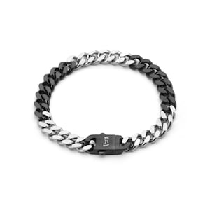 May include: A two-tone curb chain bracelet, half black and half silver. The bracelet features a black clasp with the engraved text "W.A.T.Z.". The jewellery is displayed against a white backdrop, showcasing its contrasting colours.