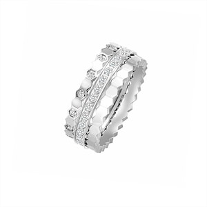 May include: Three silver rings with a honeycomb design. One ring features a row of small, clear gemstones. The rings are stacked together, creating a layered effect. The rings are set against a white background.