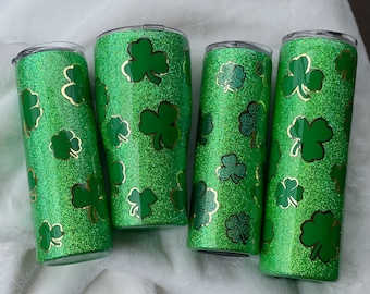 Puede incluir: Cuatro vasos de glitter verde con diseños de trébol dorado. Los vasos son perfectos para el Día de San Patricio o cualquier celebración de temática irlandesa.