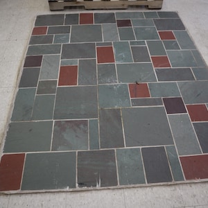 May include: A rectangular stone tile mosaic with a variety of shapes and colors. The mosaic features rectangular tiles in shades of gray, red, and brown, arranged in a random pattern. The mosaic is likely for flooring or a decorative surface.