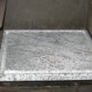 May include: A close-up of a gray stone pizza baking stone inside a wood-fired oven.