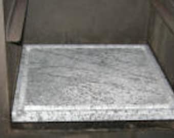 Puede incluir: Primer plano de una piedra para hornear pizza de piedra gris dentro de un horno de leña.