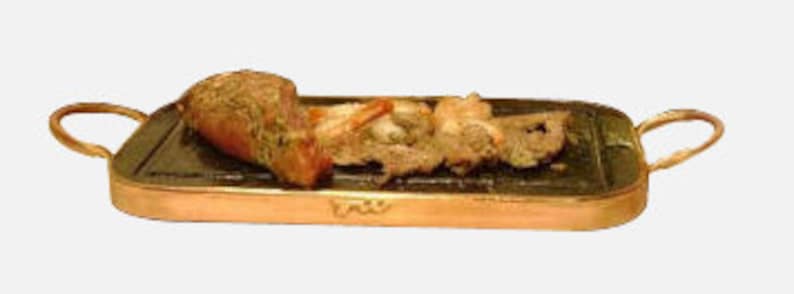 May include: A copper-colored rectangular serving tray with a black stone insert. The tray has two handles and features a small inscription on the front. The stone insert is filled with cooked meat and vegetables.