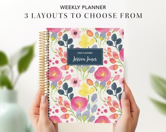 May include: A floral weekly planner with a gold spiral binding. The cover features a watercolor design of pink, yellow, and blue flowers. Text on the cover reads "2024 Planner" and "Jessica Jones". The planner is held by two hands.