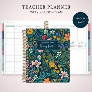 May include: A teacher planner with a floral design cover. The cover has a dark blue background with colorful flowers. The planner is spiral-bound with a gold coil and includes a weekly lesson plan layout. The text "Teacher Planner" and "Weekly Lesson Plan" are visible.