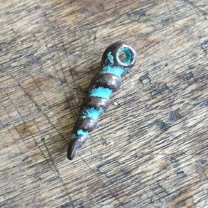 May include: A small, spiraled charm made of metal with a turquoise blue paint finish. The charm has a hole at the top for attaching to a necklace or bracelet.