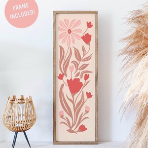 May include: A framed floral print with pink and red flowers on a light pink background. The frame is a natural wood color.