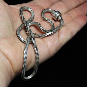 May include: A silver snake chain necklace with a magnetic clasp.