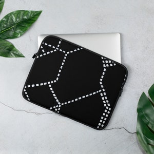 May include: Black laptop sleeve with a white geometric pattern. The sleeve is made of a soft, padded material and has a zipper closure.