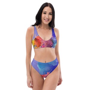 Könnte beinhalten: Ein hoch taillierter Bikini mit einem farbenfrohen Aquarelldruck. Das Oberteil und das Unterteil des Bikinis haben ein abstraktes Design in Blau, Lila, Gelb, Orange und Rot.