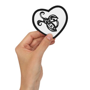 May include: A white heart-shaped patch with a black embroidered ladybug design.