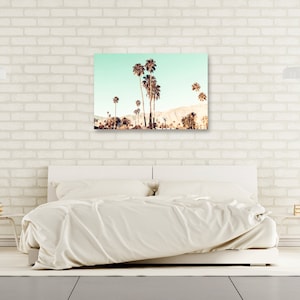 May include: A photograph of a group of palm trees against a light blue sky. The palm trees are silhouetted against the sky, and the image has a vintage feel.