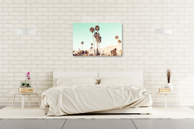 May include: A photograph of a group of palm trees against a light blue sky. The palm trees are silhouetted against the sky, and the image has a vintage feel.