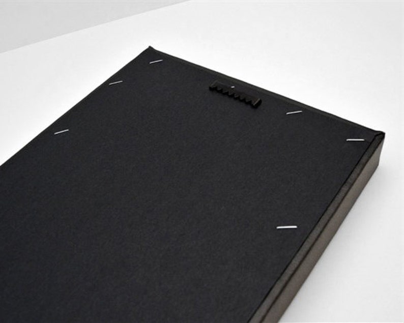 May include: The back of a black canvas print with a hanging mechanism and staples holding the canvas to the frame.