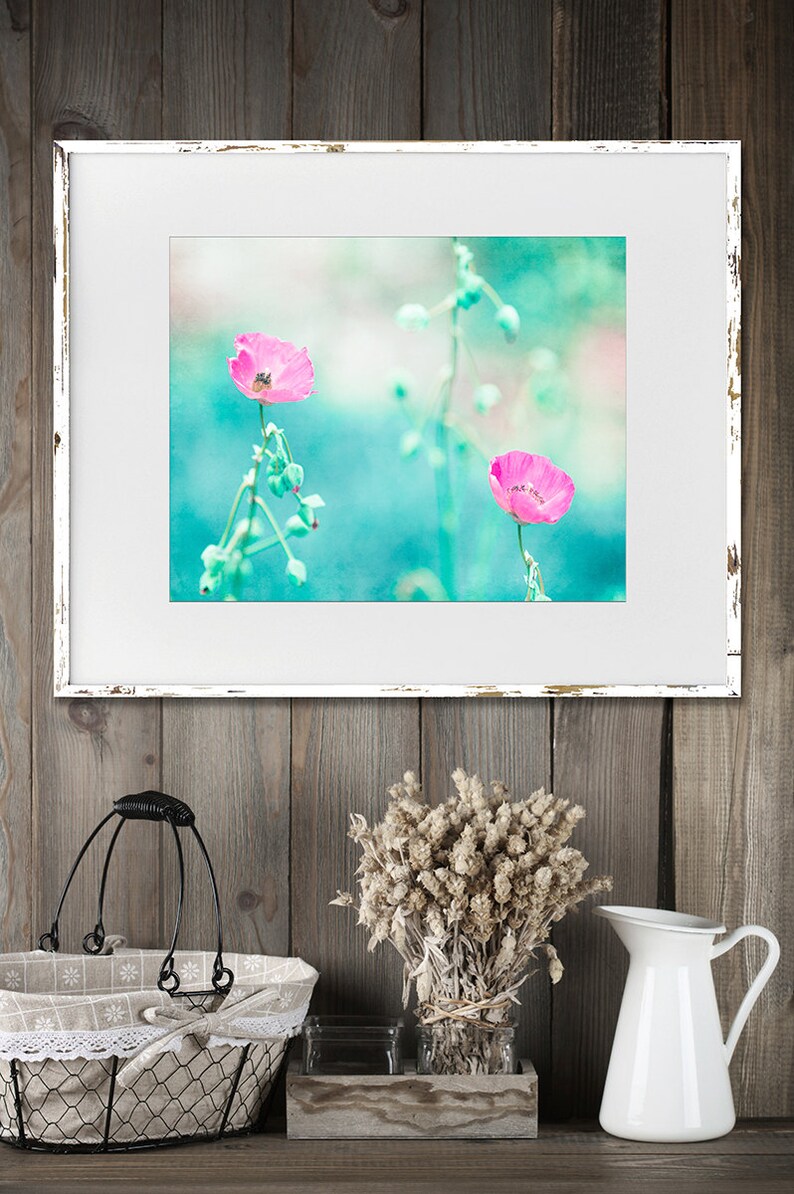 May include: A framed print of two pink flowers with green stems against a turquoise background. The frame is white with a distressed look.
