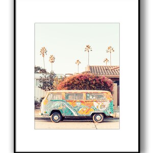 May include: A yellow vintage van with colorful psychedelic artwork, including waves, a sun, and peace signs, parked on a street with palm trees in the background.