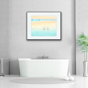 May include: A white bathtub with a framed picture of a beach scene above it. The picture shows a blue and yellow sky with two white starfish in the water.