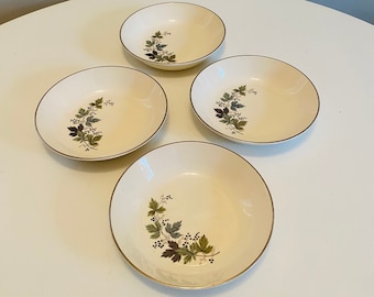 May include: Set of four white ceramic bowls with a gold rim and a floral design featuring green leaves and black berries.