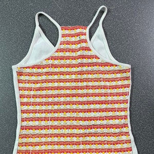 Könnte beinhalten: Ein weißes Tanktop mit einem roten und gelben Druck von Campbell's Suppendosen.