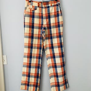 Puede incluir: Un pantalón de cuadros con un patrón rojo, azul y blanco. El pantalón tiene cierre de botón y trabillas para el cinturón.