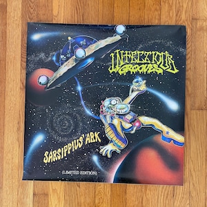 May include: A black and white poster with a cartoon astronaut in a yellow spacesuit floating in space. The astronaut is holding a small, yellow object. The poster has the text "Infectious Grooves" and "SarsIPPIUS' ARK (Limited Edition)" on it.