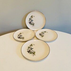 Op de afbeelding: Set van drie witte keramische dessertborden met een gouden rand en een groen en bruin bloemenontwerp.