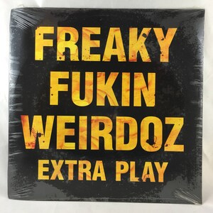 Może przedstawiać: Czarna płyta winylowa z żółtym tekstem, który brzmi "FREAKY FUKIN WEIRDOZ EXTRA PLAY".