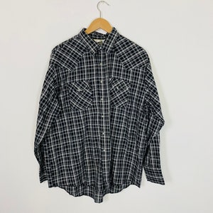 May include: A black and white plaid long-sleeve button-down shirt with two chest pockets and a pointed collar.