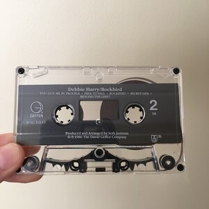 May include: A black cassette tape with a clear plastic case. The tape is labeled "Debbie Harry/Rockbird" and features the songs "You Got Me In Trouble", "Free To Fall", "Rockbird", "Secret Life", and "Beyond The Limit". The tape is a Geffen Records release with the catalog number M5G 24123.