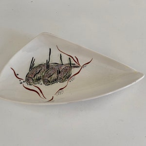 May include: A white triangular ceramic serving dish with a brown and green design of fish and seaweed.
