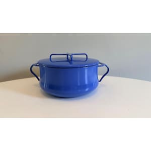 May include: A blue enamel cooking pot with a matching lid and two side handles. The pot is round with a glossy finish. The lid has a handle for easy removal. This kitchenware is perfect for cooking and serving.