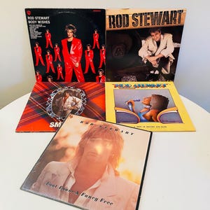 Puede incluir: Una colección de discos de vinilo de Rod Stewart. Las portadas de los álbumes presentan imágenes de Rod Stewart en varias poses, con títulos como "Body Wishes" y "Foot Loose & Fancy Free". Las portadas son de varios colores, incluyendo rojo, amarillo y negro.