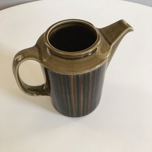 Puede incluir: Una cafetera de cer&aacute;mica rayada en marr&oacute;n y negro con asa y pico.