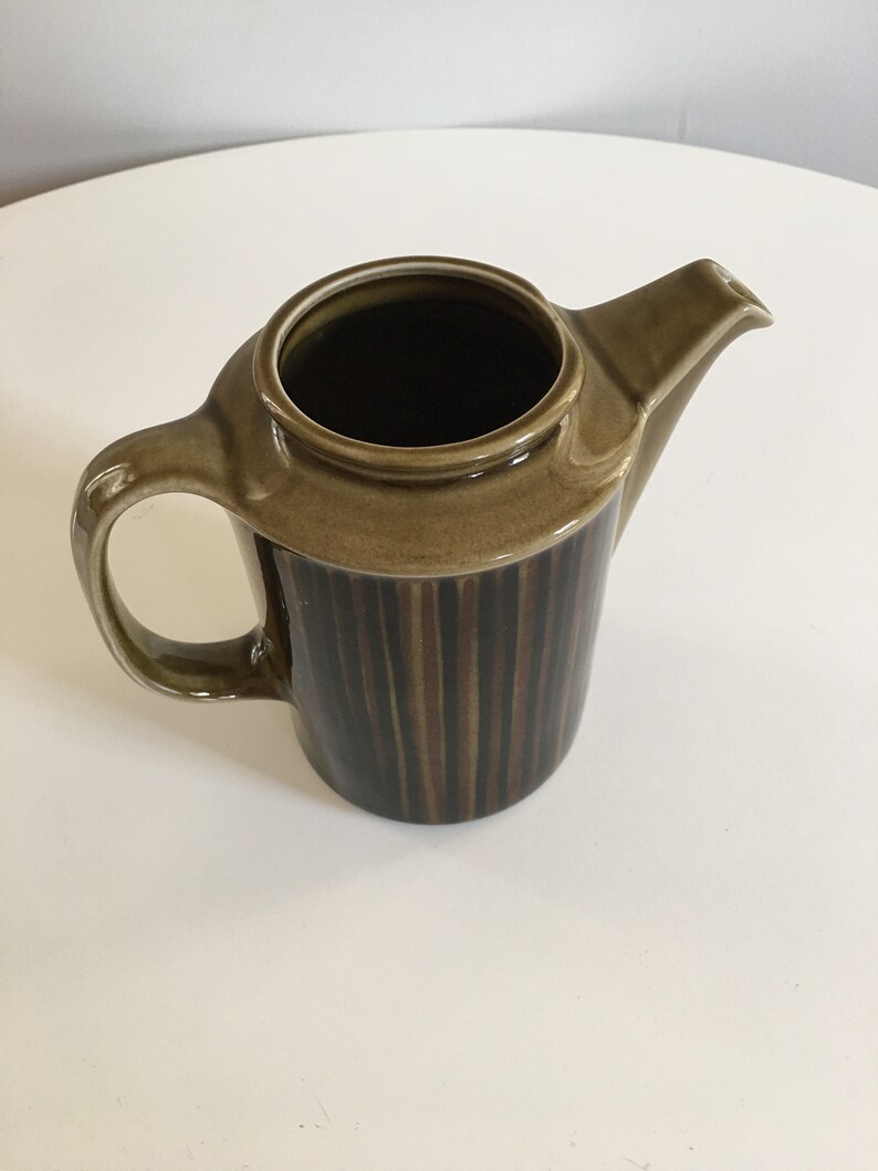 Puede incluir: Una cafetera de cer&aacute;mica rayada en marr&oacute;n y negro con asa y pico.